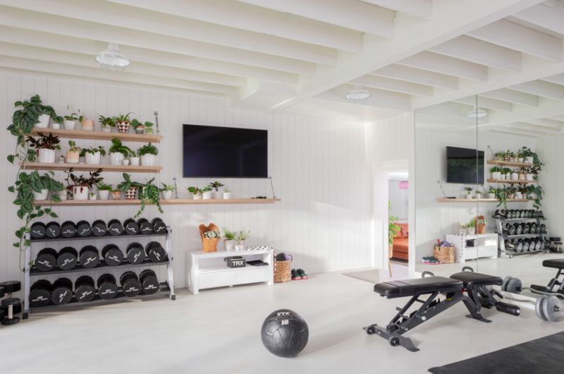 Fully remodeled home gym with integrated living spaces, featuring modern equipment, ample natural light, and stylish indoor plants, reflecting a seamless renovation design.